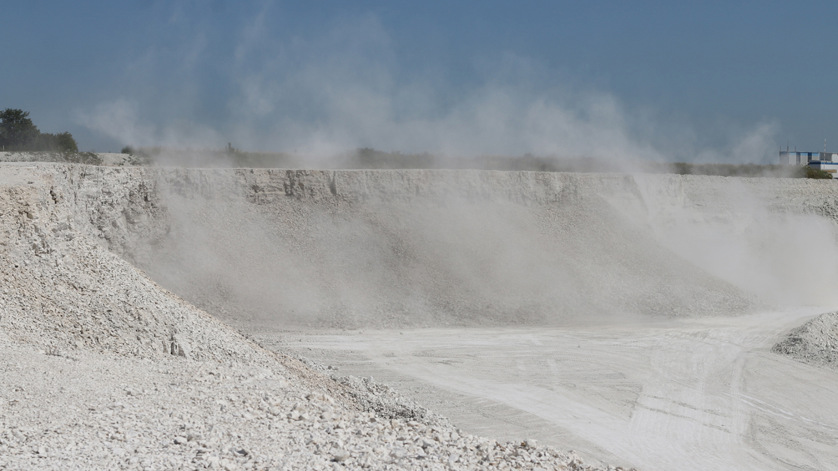 Gesprengtes Lockergestein rutscht die Wand des Steinbruchs hinab